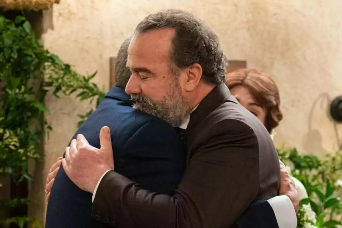 Dos homes —un d’ells Ròmul a ‘La Promesa’— s’abracen amb força en un ambient interior decorat amb plantes, mostrant una expressió de consol i suport emocional. Dos homes —un d’ells Ròmul a ‘La Promesa’— s’abracen amb força en un ambient interior decorat amb plantes, mostrant una expressió de consol i suport emocional.