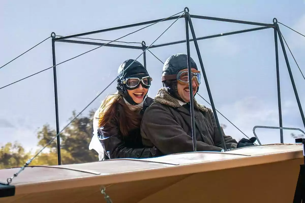 Arturo Sancho i Sara Font, somrients amb ulleres i cascos d’aviador, gaudeixen d’un passeig en un avió antic a La Promesa. Arturo Sancho i Sara Font, somrients amb ulleres i cascos d’aviador, gaudeixen d’un passeig en un avió antic a La Promesa.