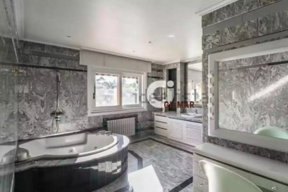 Bany ampli i elegant amb jacuzzi, parets i terra de marbre gris, finestra gran i tocador amb mirall il·luminat. Bany ampli i elegant amb jacuzzi, parets i terra de marbre gris, finestra gran i tocador amb mirall il·luminat.