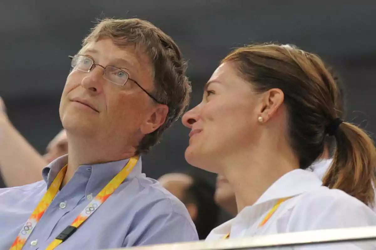 Bill Gates i Melinda amb acreditacions grogues observen alguna cosa cap amunt en un esdeveniment esportiu.