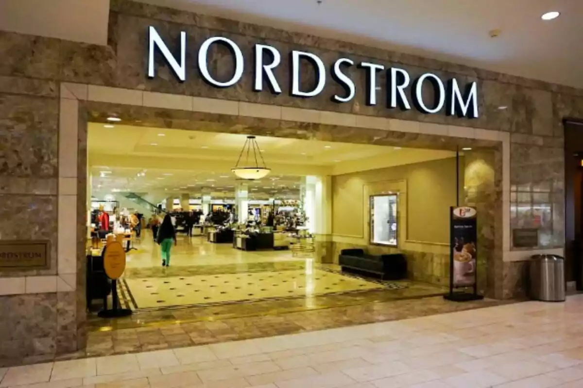 Entrada de una tienda Nordstrom en un centro comercial con personas caminando en el interior y productos exhibidos Entrada de una tienda Nordstrom en un centro comercial con personas caminando en el interior y productos exhibidos