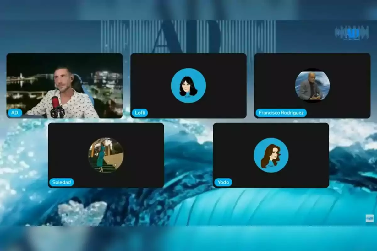 Captura de pantalla d’una videotrucada grupal amb cinc participants, on només un té la càmera encesa —que és l’Antonio David Flores— i la resta mostren avatars o fotos de perfil sobre un fons blau amb ones. Captura de pantalla d’una videotrucada grupal amb cinc participants, on només un té la càmera encesa —que és l’Antonio David Flores— i la resta mostren avatars o fotos de perfil sobre un fons blau amb ones.