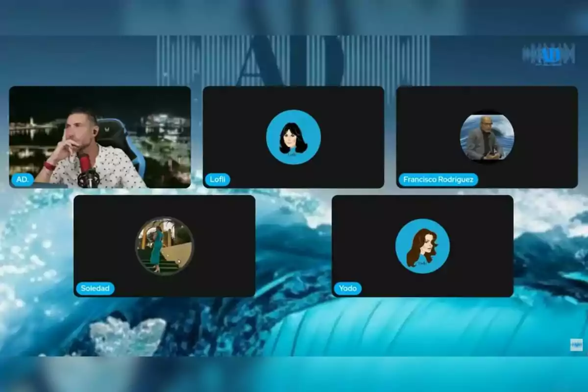 Captura de pantalla d’una videotrucada grupal amb cinc participants, on només un té la càmera encesa —que és l’Antonio David Flores— i la resta mostren avatars o fotos de perfil sobre un fons blau amb ones. Captura de pantalla d’una videotrucada grupal amb cinc participants, on només un té la càmera encesa —que és l’Antonio David Flores— i la resta mostren avatars o fotos de perfil sobre un fons blau amb ones.