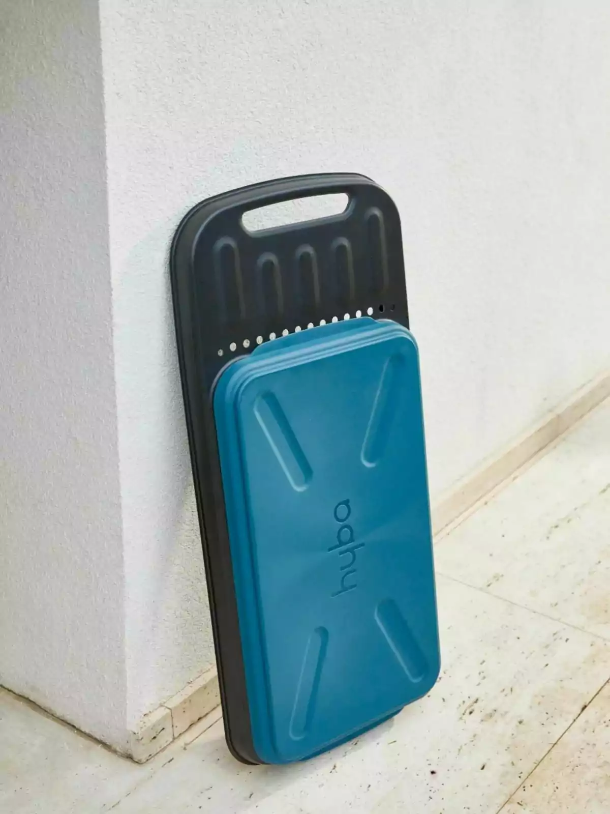Banc d’exercici blau i negre recolzat contra una paret blanca sobre un terra de marbre Banc d’exercici blau i negre recolzat contra una paret blanca sobre un terra de marbre