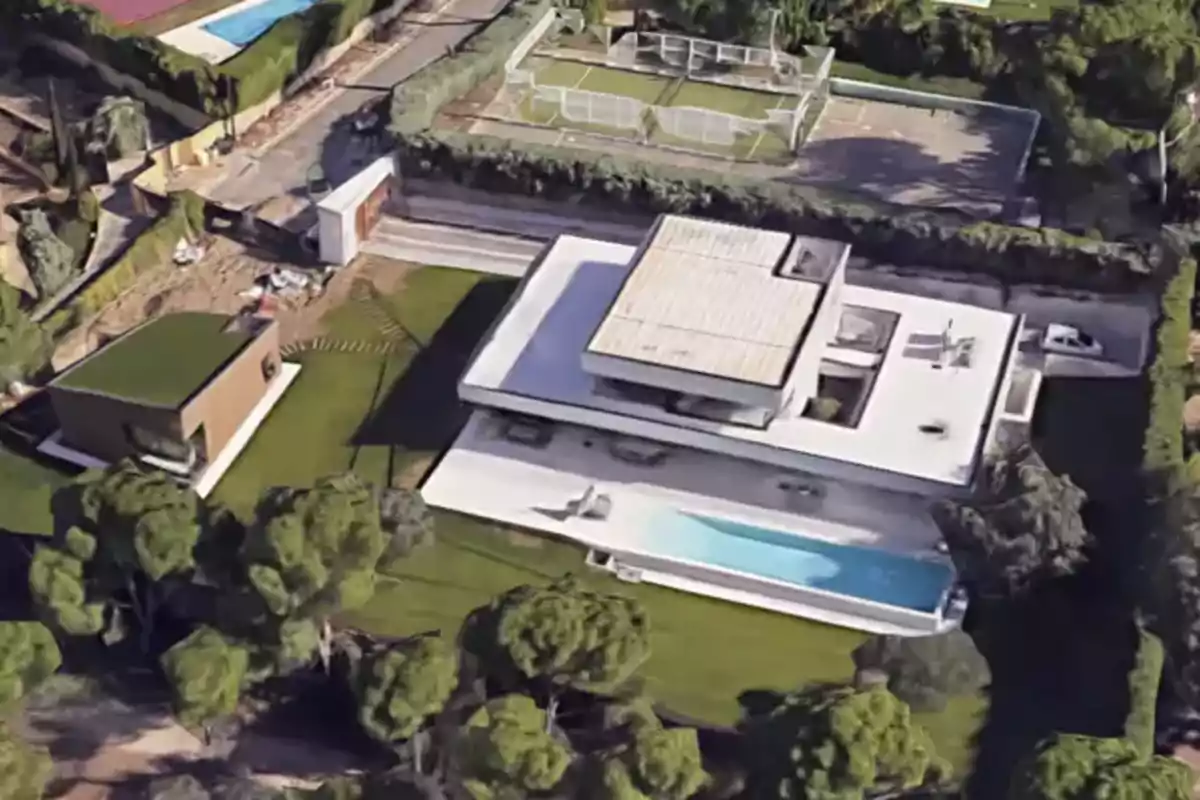 Vista aérea de una casa moderna con piscina, jardín amplio y una cancha deportiva al fondo rodeada de árboles y vegetación Vista aérea de una casa moderna con piscina, jardín amplio y una cancha deportiva al fondo rodeada de árboles y vegetación