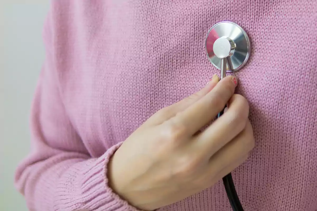 Person using a stethoscope over a pink sweater Person using a stethoscope over a pink sweater