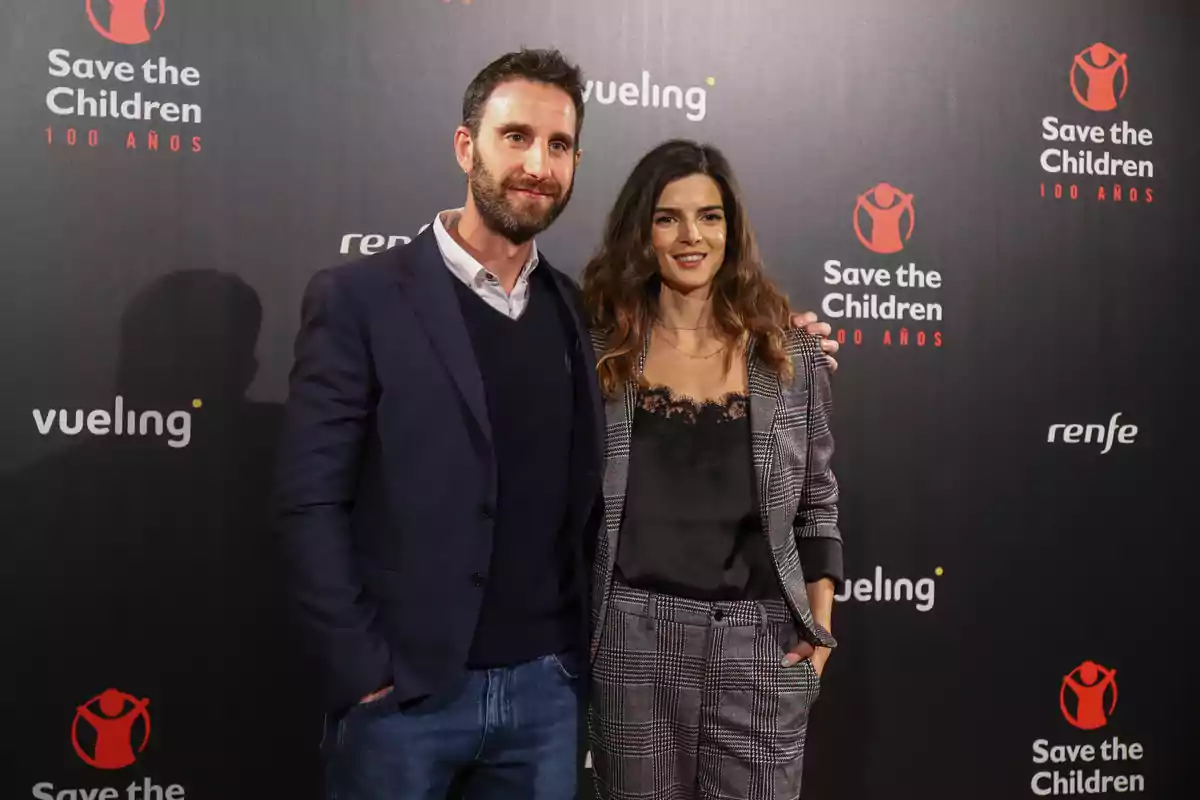 Dani Rovira i Clara Lago posen junts en un esdeveniment de Save the Children amb fons negre i logotips de patrocinadors Dani Rovira i Clara Lago posen junts en un esdeveniment de Save the Children amb fons negre i logotips de patrocinadors