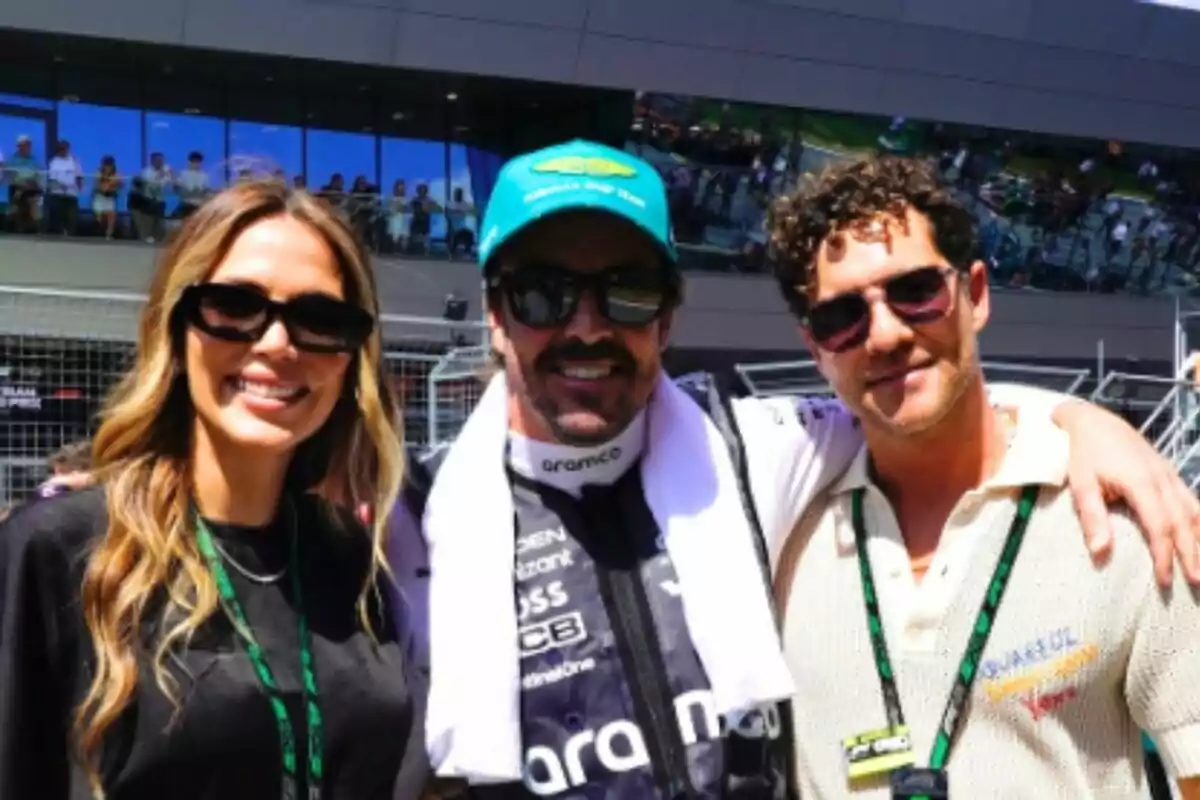 Tres persones, que són Rosanna Zanetti, Fernando Alonso i David Bisbal, somriuen portant ulleres de sol en un esdeveniment esportiu a l’aire lliure, amb una multitud i una estructura moderna de fons. Tres persones, que són Rosanna Zanetti, Fernando Alonso i David Bisbal, somriuen portant ulleres de sol en un esdeveniment esportiu a l’aire lliure, amb una multitud i una estructura moderna de fons.