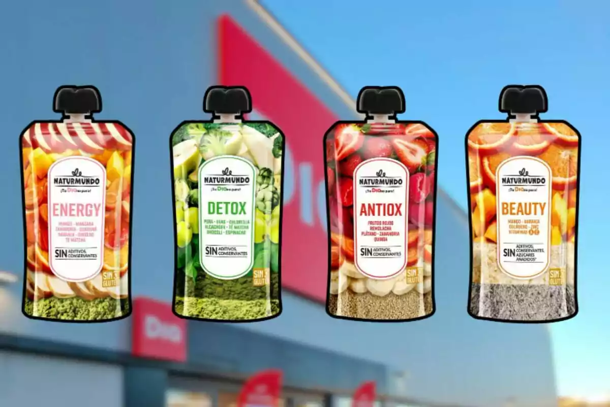 Cuatro sobres de purés de frutas y verduras de la marca Naturmundo con diferentes etiquetas de Energy, Detox, Antiox y Beauty frente a una tienda. Cuatro sobres de purés de frutas y verduras de la marca Naturmundo con diferentes etiquetas de Energy, Detox, Antiox y Beauty frente a una tienda.