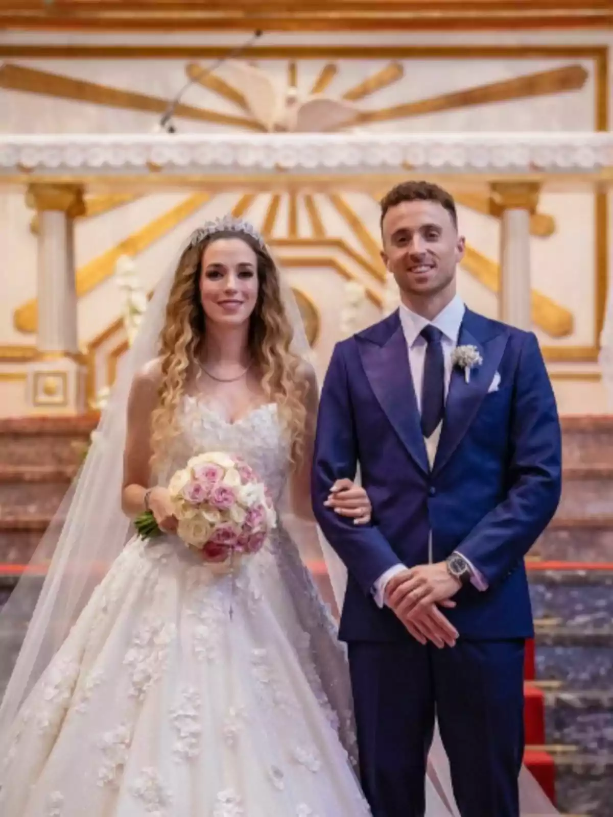 Newlywed couple posing together in a church, the bride is wearing a white lace dress and holding a bouquet of flowers, the groom, who is Diogo Jota, is dressed in a dark blue suit. Newlywed couple posing together in a church, the bride is wearing a white lace dress and holding a bouquet of flowers, the groom, who is Diogo Jota, is dressed in a dark blue suit.