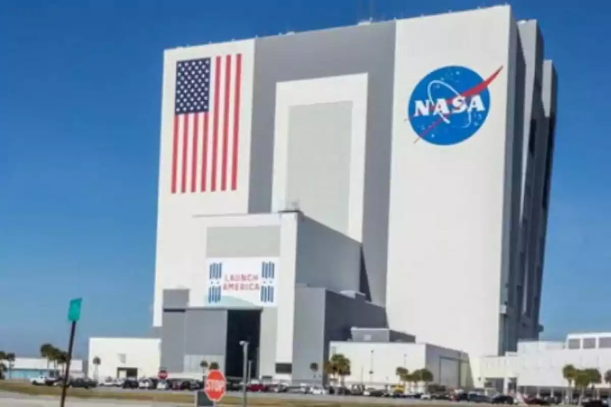 Edificio de la NASA con una gran bandera de Estados Unidos y el logotipo de la agencia en la fachada bajo un cielo despejado Edificio de la NASA con una gran bandera de Estados Unidos y el logotipo de la agencia en la fachada bajo un cielo despejado