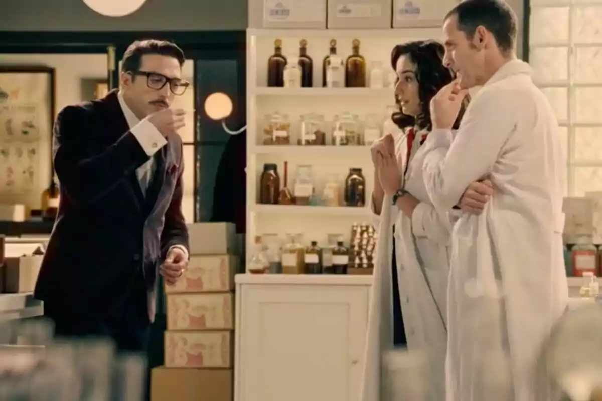 Three people in a laboratory, two in white coats watch a man in a suit—who is Bruno Tamarit—taste the contents of a cup. Three people in a laboratory, two in white coats watch a man in a suit—who is Bruno Tamarit—taste the contents of a cup.