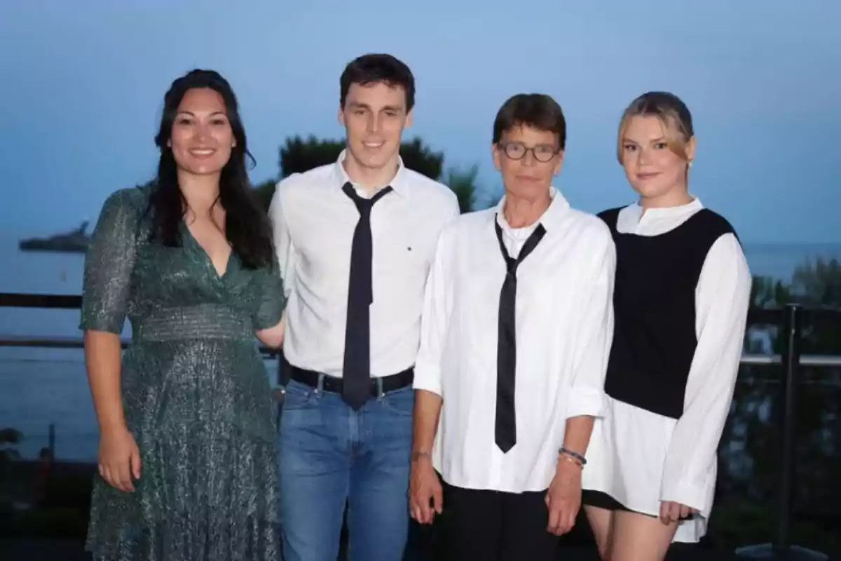 Quatre persones posen juntes a l’aire lliure amb el mar de fons i arbres darrere, totes vestides de manera elegant i informal. Quatre persones posen juntes a l’aire lliure amb el mar de fons i arbres darrere, totes vestides de manera elegant i informal.