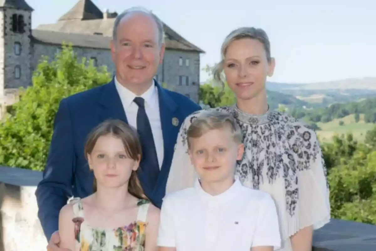 Una família de quatre persones, que són l'Albert de Mònaco, la Charlene i els seus dos fills, posen a l'aire lliure davant d'un castell i un paisatge verd.