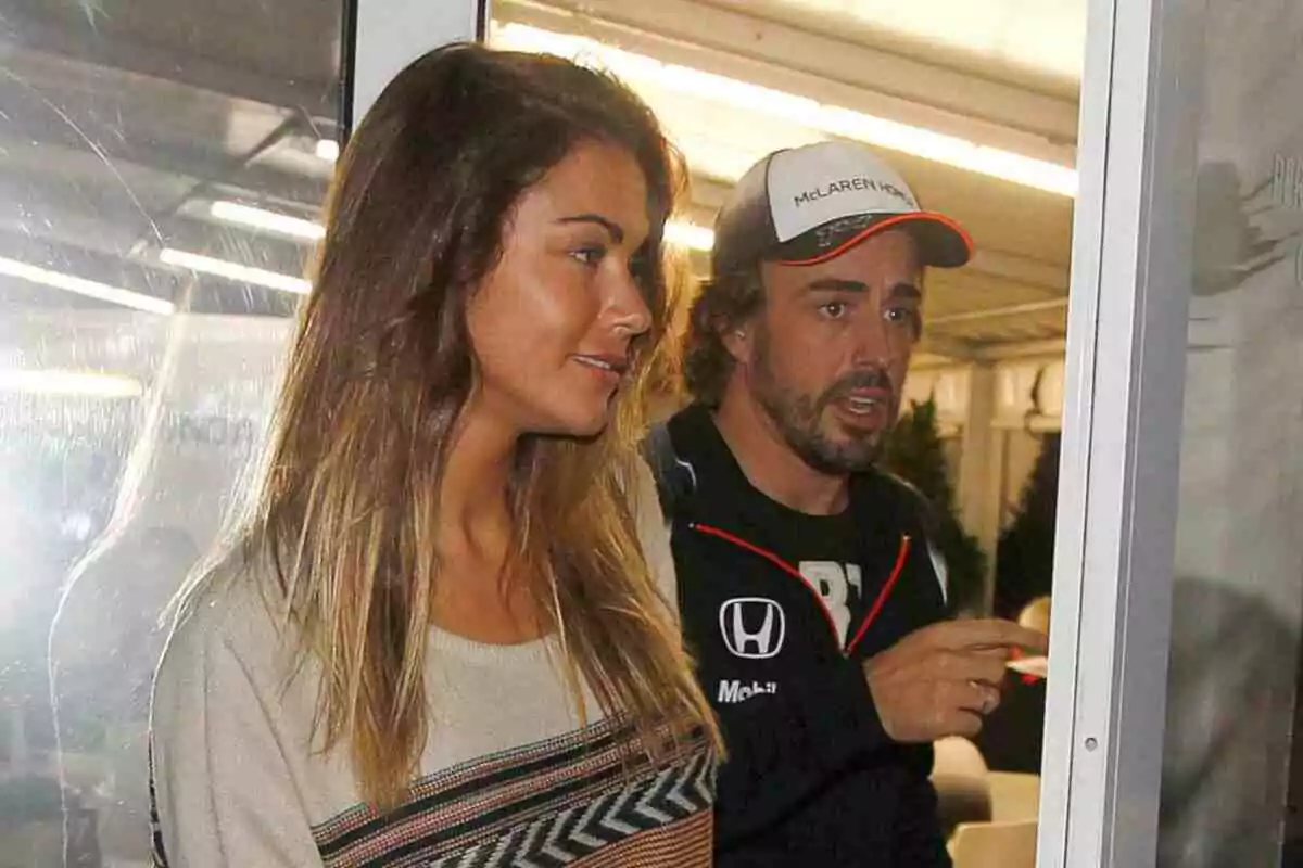 Lara Álvarez y Fernando Alonso con gorra y chaqueta de McLaren Honda están juntos en un ambiente interior iluminado Lara Álvarez y Fernando Alonso con gorra y chaqueta de McLaren Honda están juntos en un ambiente interior iluminado
