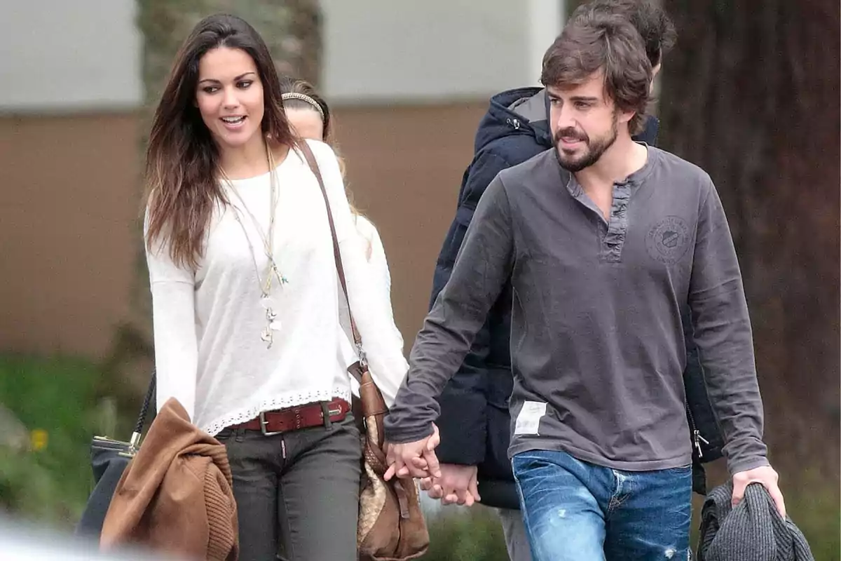 Lara Álvarez y Fernando Alonso caminando de la mano al aire libre mientras conversan y sonríen Lara Álvarez y Fernando Alonso caminando de la mano al aire libre mientras conversan y sonríen