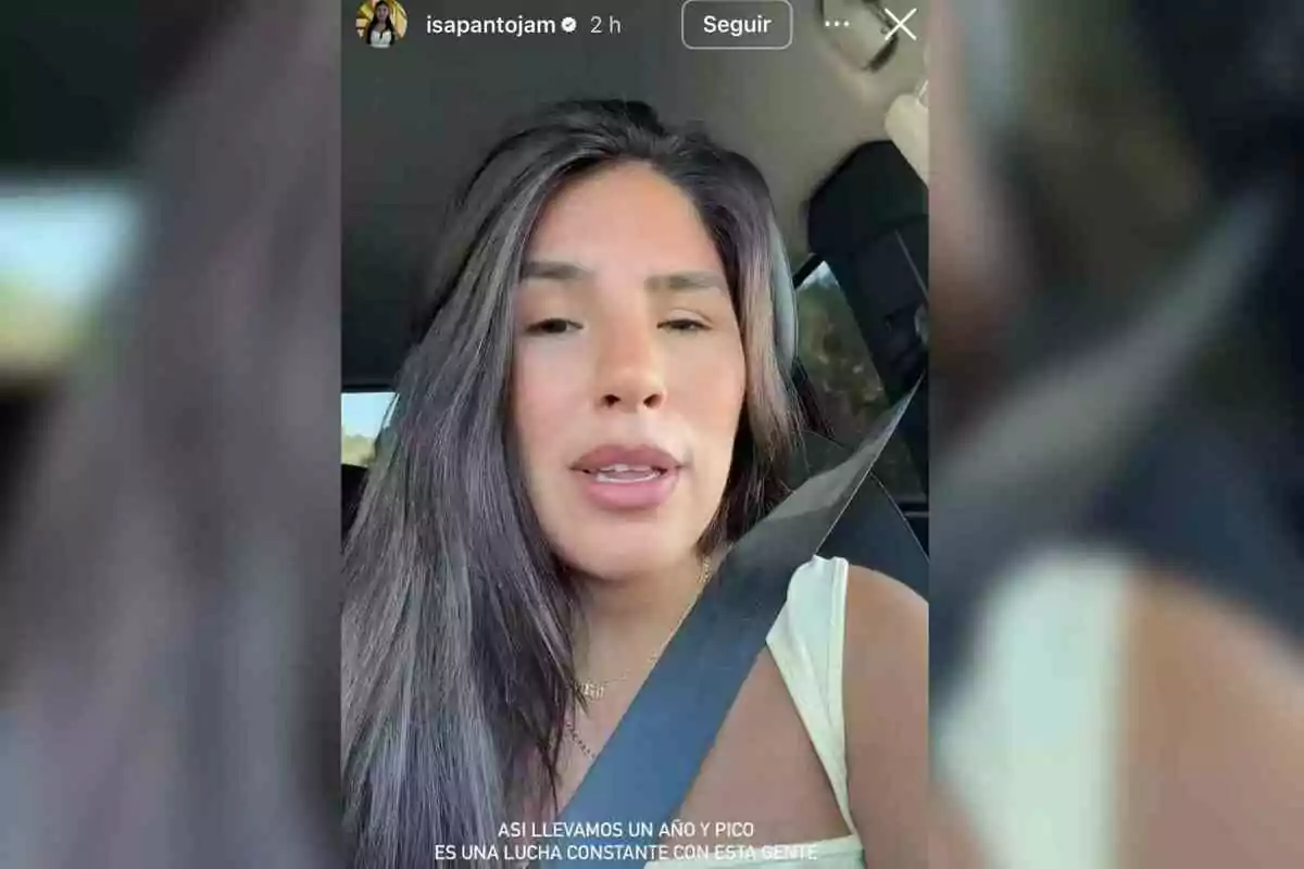 Isa Pantoja de cabello largo y lacio sentada en un automóvil usando cinturón de seguridad y camiseta clara mientras graba un video selfie
