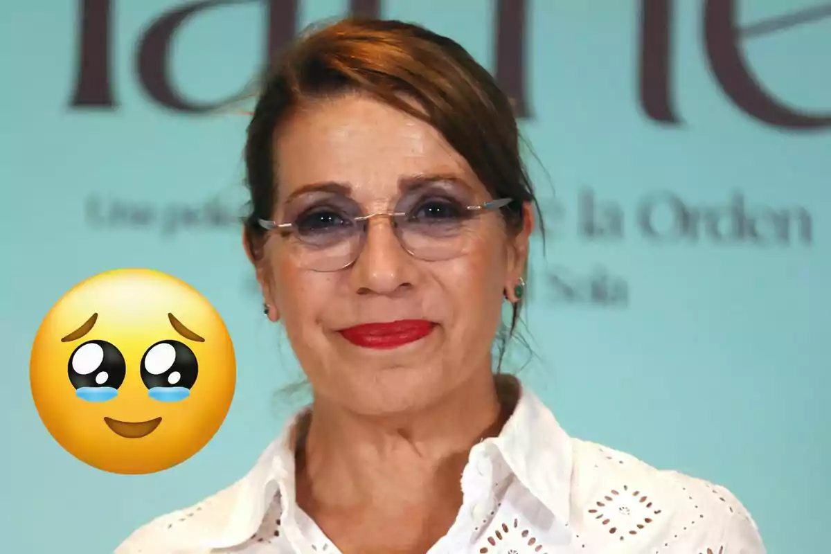 Dona de cabells castanys amb ulleres i llavis vermells somriu lleument mentre un emoji de carona amb ulls brillants i llàgrimes apareix al seu costat.