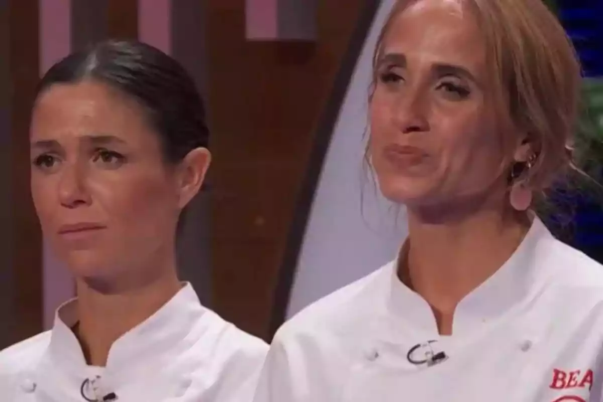 Gabriela i Bea amb jaquetes de xef blanques mostren expressions serioses i emotives en un plató de competició culinària de MasterChef. Gabriela i Bea amb jaquetes de xef blanques mostren expressions serioses i emotives en un plató de competició culinària de MasterChef.