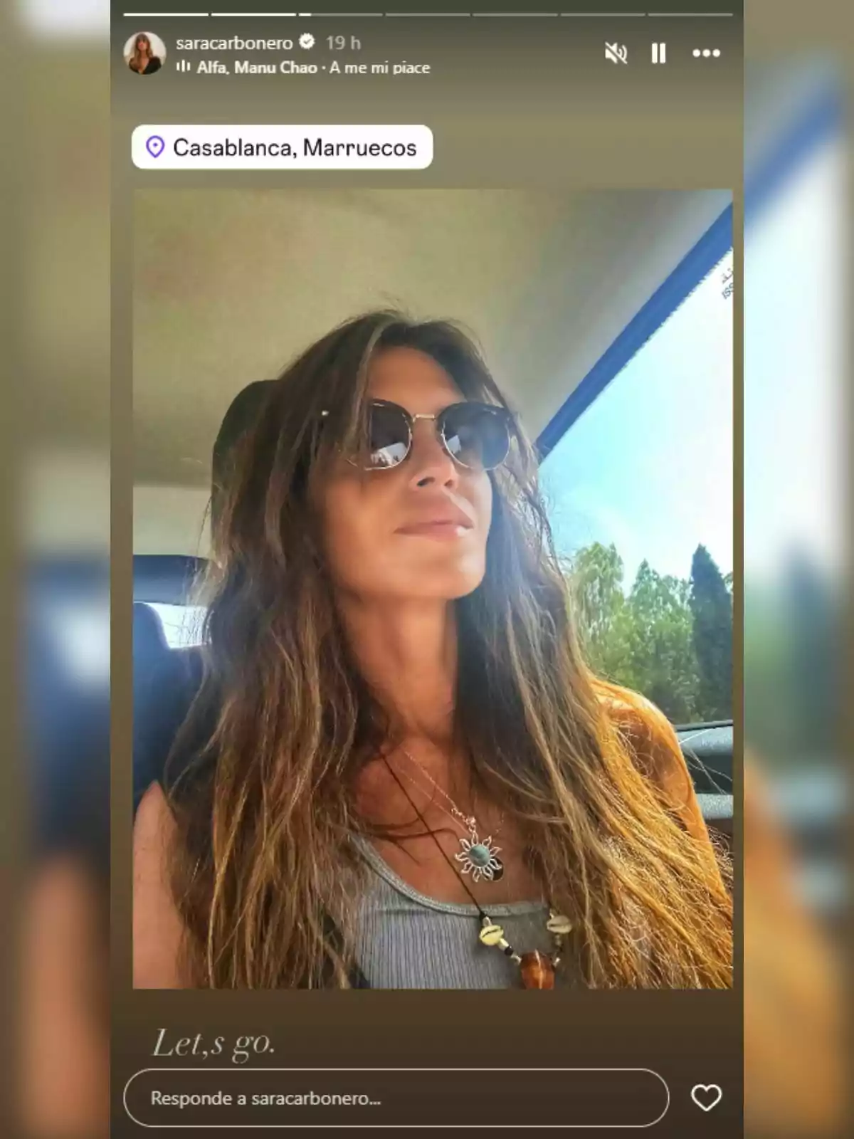 Sara Carbonero amb ulleres de sol i cabell llarg asseguda en un cotxe, portant un collaret i una samarreta grisa, amb un paisatge exterior assolellat visible per la finestra i la ubicació Casablanca, Marroc indicada a la imatge.