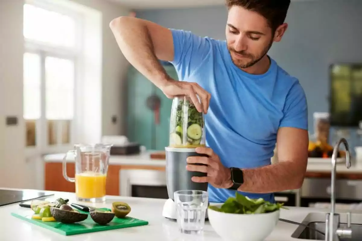 Home preparant un batut saludable amb fruites i verdures en una liquadora a la cuina Home preparant un batut saludable amb fruites i verdures en una liquadora a la cuina