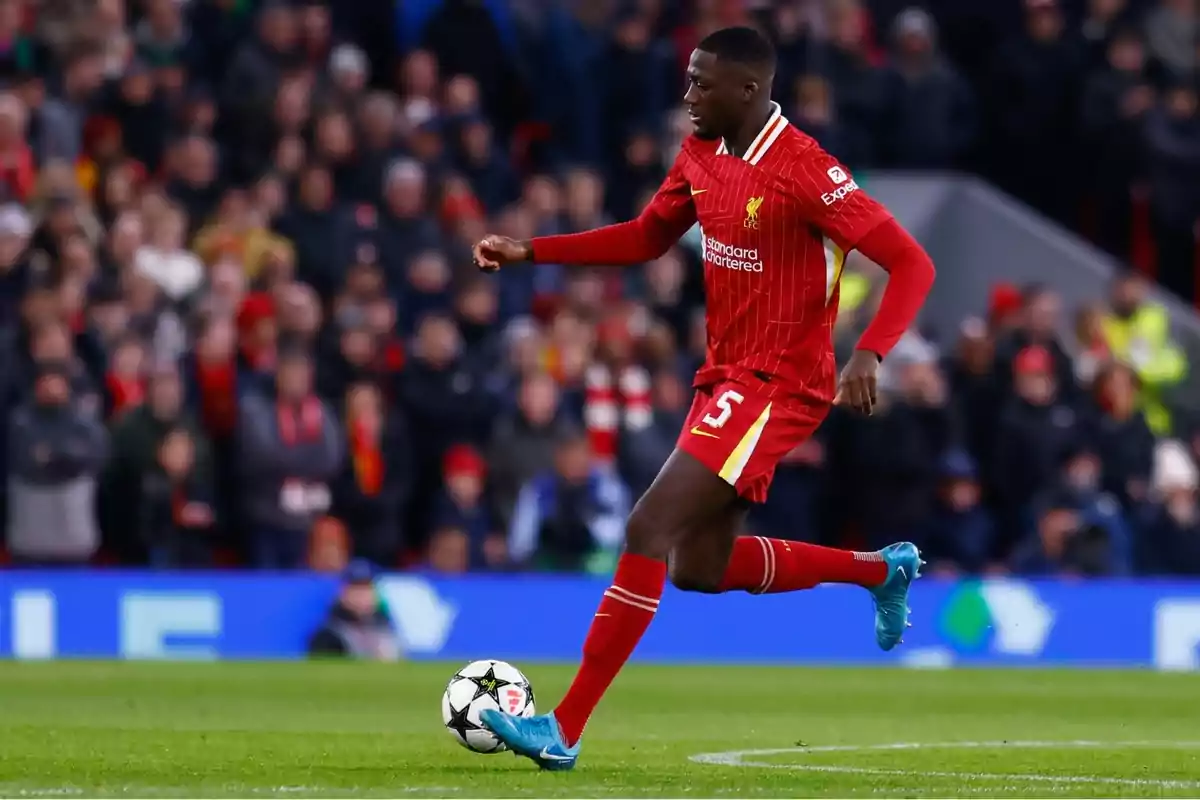 Futbolista del Liverpool con uniforme rojo controla el balón durante un partido en un estadio lleno de espectadores