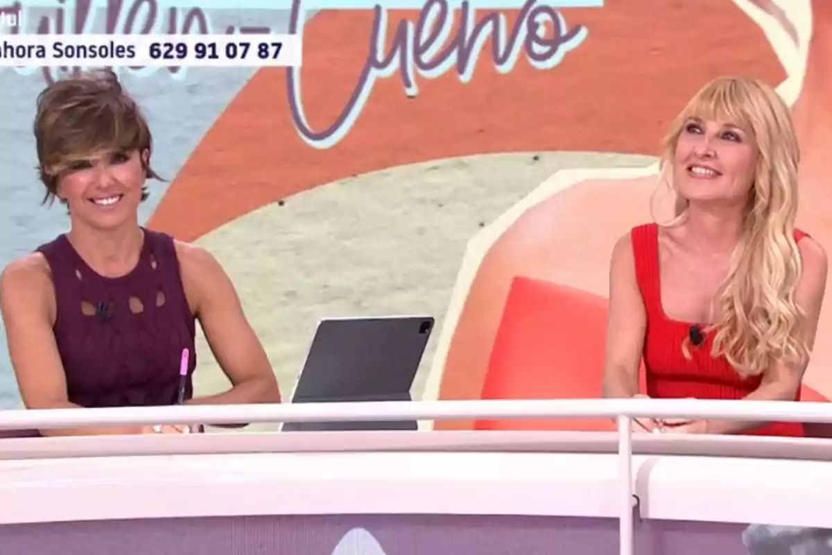 Sonsoles Ónega y Cayetana Guillén Cuervo sonrientes sentadas en un set de televisión con fondo colorido y una tableta sobre la mesa Sonsoles Ónega y Cayetana Guillén Cuervo sonrientes sentadas en un set de televisión con fondo colorido y una tableta sobre la mesa