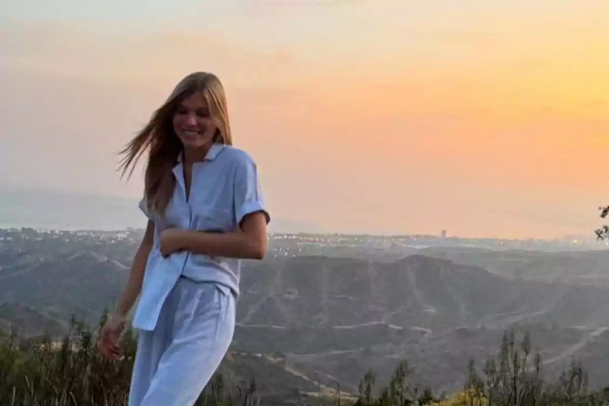 Smiling young man in light clothing standing in a mountainous landscape at sunset Smiling young man in light clothing standing in a mountainous landscape at sunset