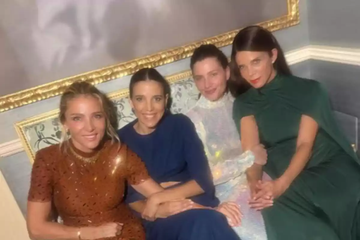 Cuatro mujeres elegantemente vestidas están sentadas juntas en un sofá, sonriendo y posando para la cámara en un ambiente sofisticado. Cuatro mujeres elegantemente vestidas están sentadas juntas en un sofá, sonriendo y posando para la cámara en un ambiente sofisticado.