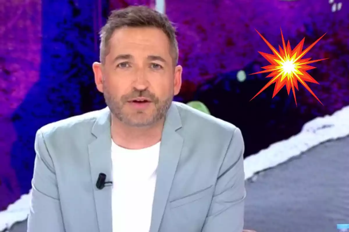 Frank Blanco de cabello corto y barba con chaqueta clara frente a un fondo morado y una explosión gráfica amarilla y roja a su lado
