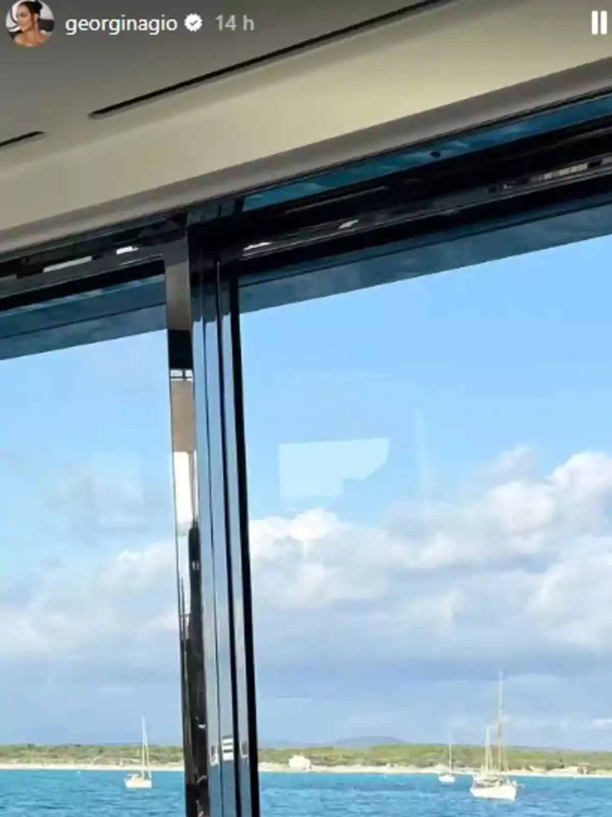 Vista des de l'interior d'un iot cap al mar amb velers i cel blau amb núvols Vista des de l'interior d'un iot cap al mar amb velers i cel blau amb núvols
