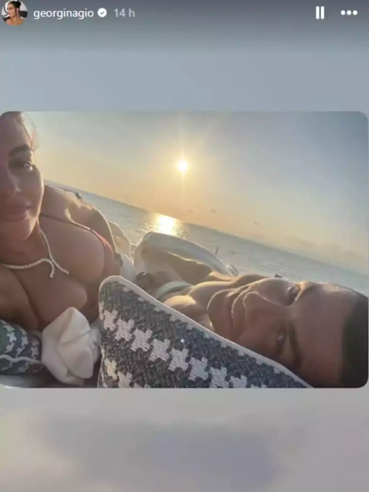 Parella estirada sobre coixins gaudint d’una posta de sol a la platja Parella estirada sobre coixins gaudint d’una posta de sol a la platja
