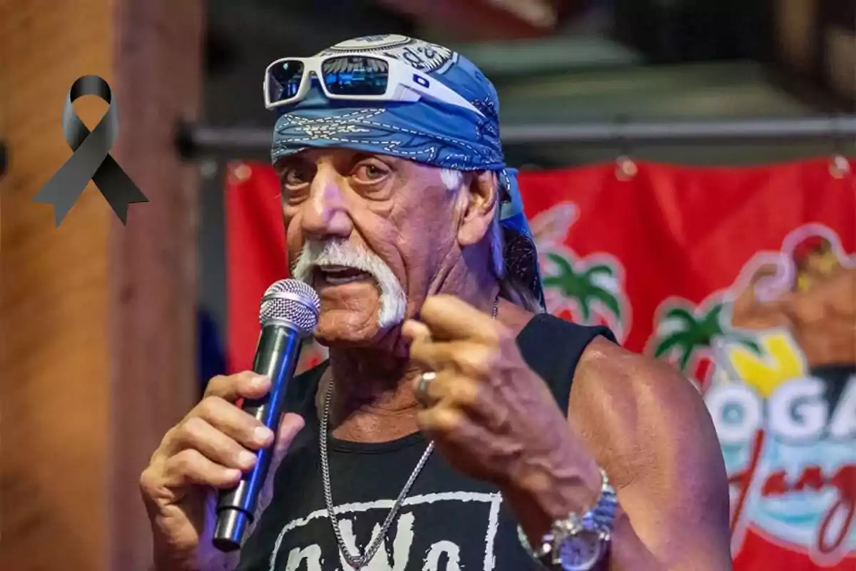 Hulk Hogan mayor con bandana azul y gafas en la cabeza hablando por micrófono con un listón negro de luto en la esquina superior izquierda