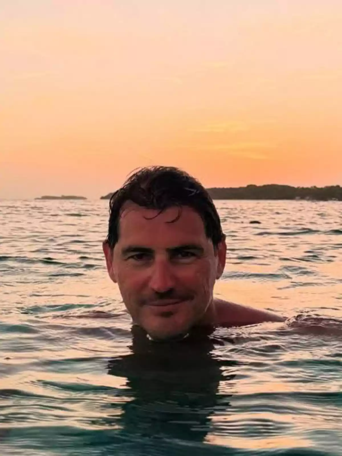 Iker Casillas nadando en el mar al atardecer con el cielo anaranjado de fondo Iker Casillas nadando en el mar al atardecer con el cielo anaranjado de fondo
