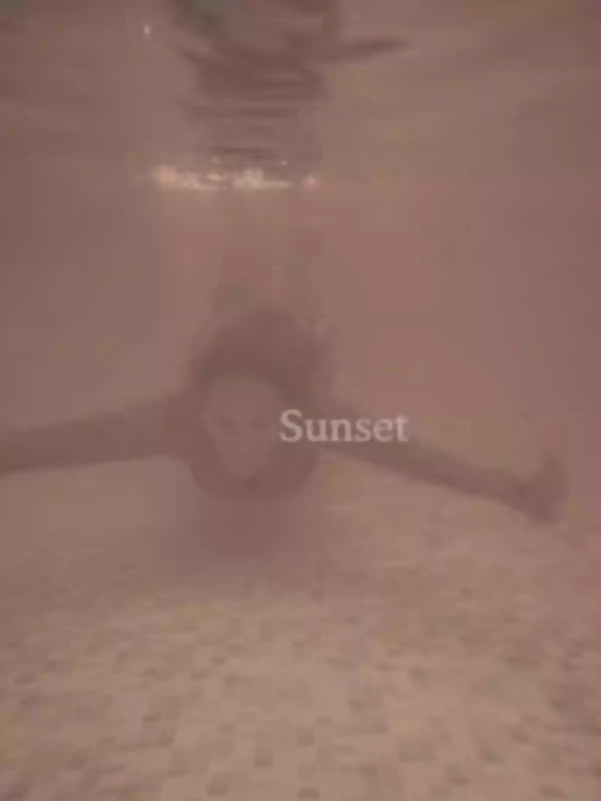 Persona nedant sota l’aigua en una piscina amb un filtre càlid i la paraula Sunset al centre Persona nedant sota l’aigua en una piscina amb un filtre càlid i la paraula Sunset al centre