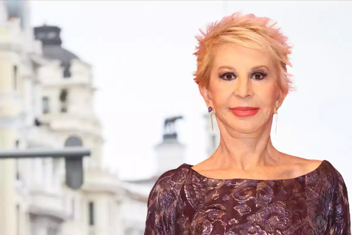 Dona de cabell curt ros amb vestit morat estampat posant davant d’un fons urbà desenfocat