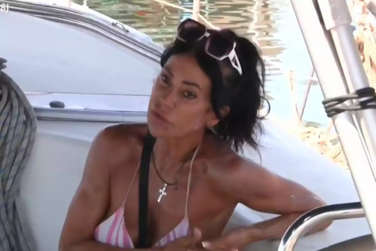 Maite Galdeano de cabello oscuro con gafas de sol en la cabeza y bikini de rayas sentada en un bote junto al agua Maite Galdeano de cabello oscuro con gafas de sol en la cabeza y bikini de rayas sentada en un bote junto al agua