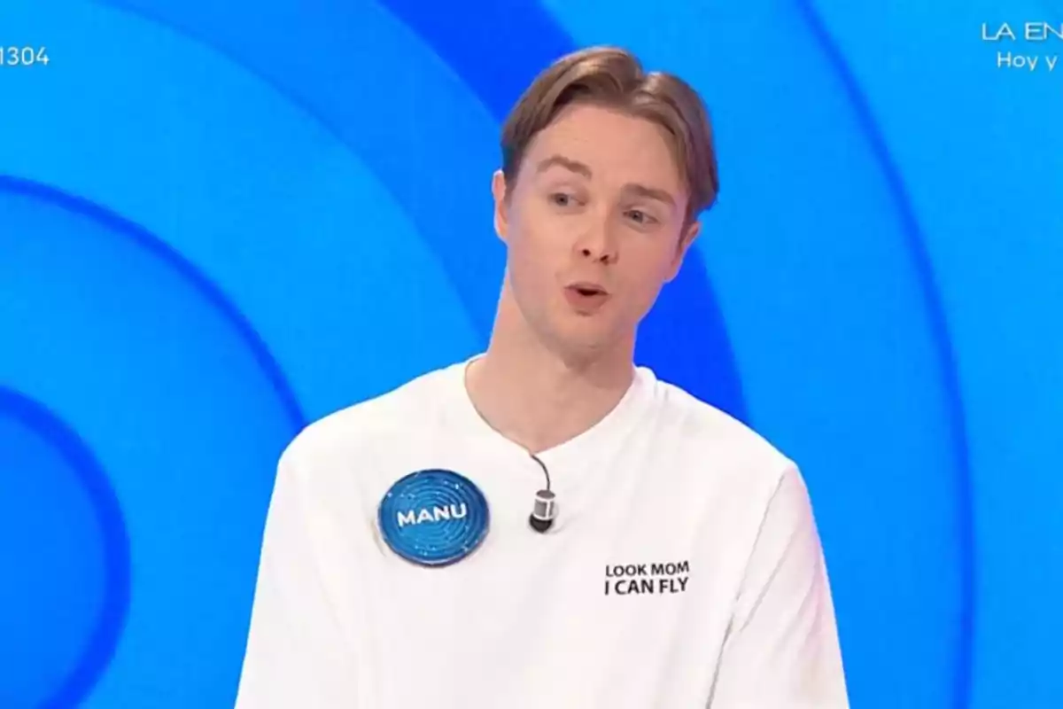 Young man in a white t-jersey with a microphone participating in a television show with a blue background Young man in a white t-jersey with a microphone participating in a television show with a blue background