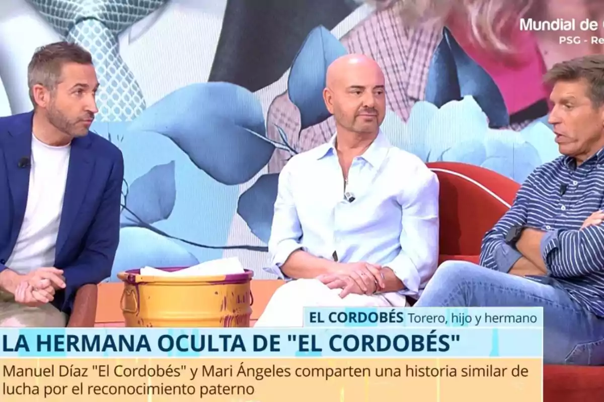 Tres hombres sentados conversan en un programa de televisión con un fondo colorido y un rótulo en pantalla que menciona la historia de la hermana oculta de El Cordobés Tres hombres sentados conversan en un programa de televisión con un fondo colorido y un rótulo en pantalla que menciona la historia de la hermana oculta de El Cordobés