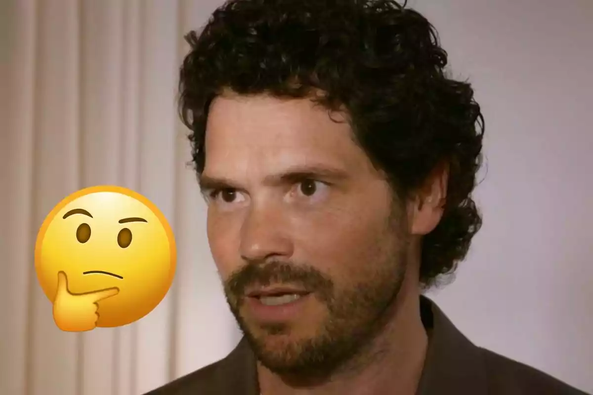Home de cabells arrissats i barba amb expressió seriosa al costat d’un emoji de cara pensativa