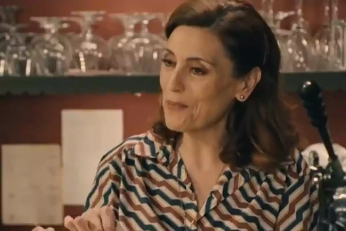 Pepa Aniorte de cabello castaño y ondulado con camisa de rayas de colores conversando en un ambiente de restaurante con copas de vidrio al fondo