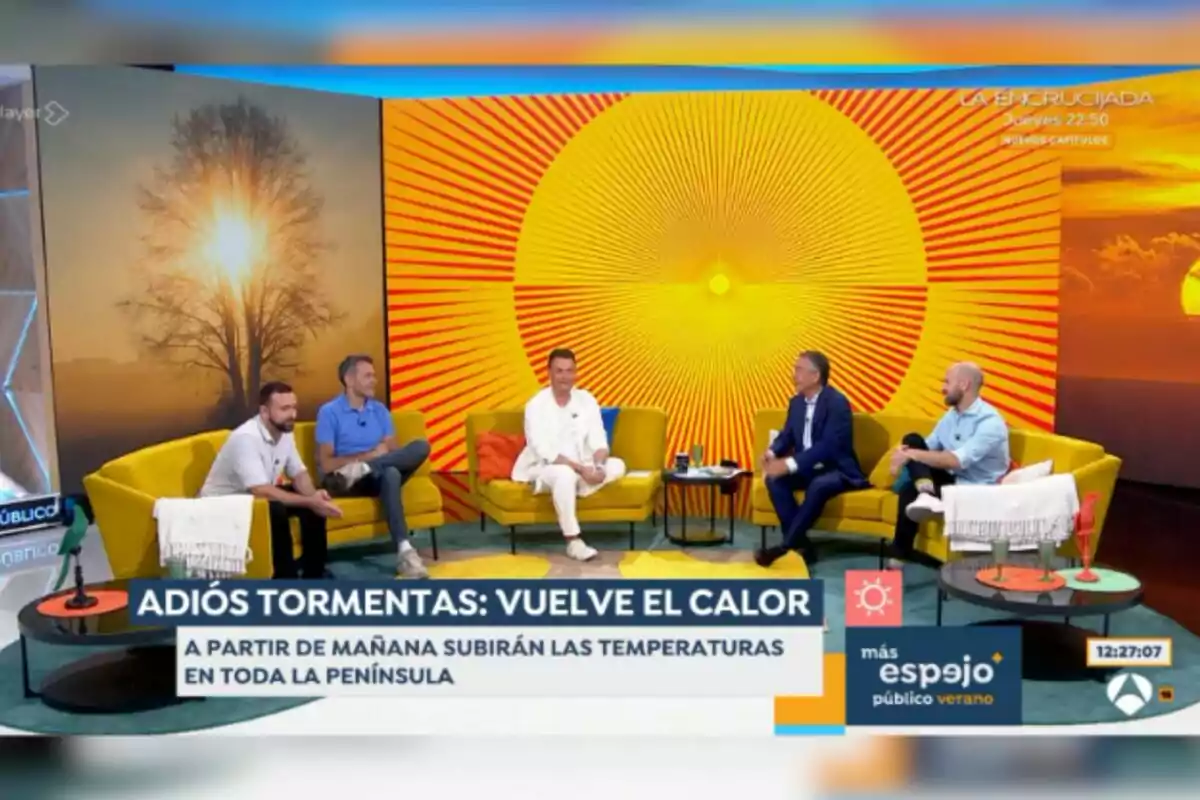 Cinco personas conversan en un set de televisión con decoración veraniega y colores cálidos, sentados en sofás amarillos, con un fondo de sol radiante y un mensaje en pantalla que anuncia el regreso del calor y el aumento de temperaturas en la península. Cinco personas conversan en un set de televisión con decoración veraniega y colores cálidos, sentados en sofás amarillos, con un fondo de sol radiante y un mensaje en pantalla que anuncia el regreso del calor y el aumento de temperaturas en la península.