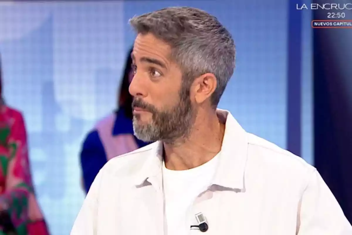 Home de cabells i barba canosos amb jaqueta blanca participant en un programa de televisió Home de cabells i barba canosos amb jaqueta blanca participant en un programa de televisió