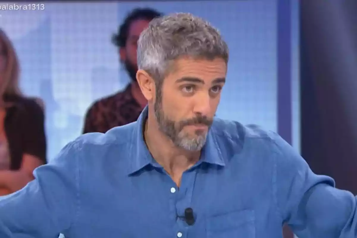 Roberto Leal de cabello canoso y barba con camisa azul en un estudio de televisión mirando hacia el frente con expresión seria Roberto Leal de cabello canoso y barba con camisa azul en un estudio de televisión mirando hacia el frente con expresión seria