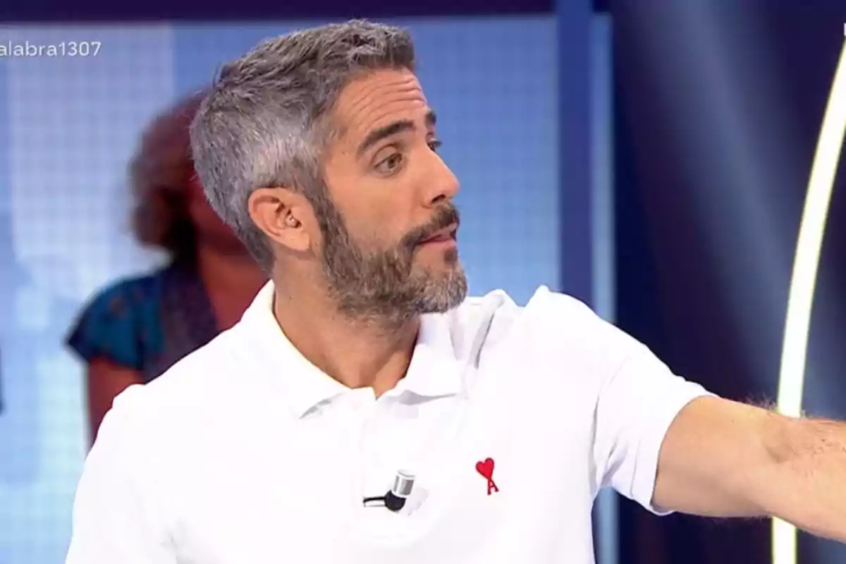 Home de cabells i barba canosos amb camisa polo blanca participant en un programa de televisió Home de cabells i barba canosos amb camisa polo blanca participant en un programa de televisió