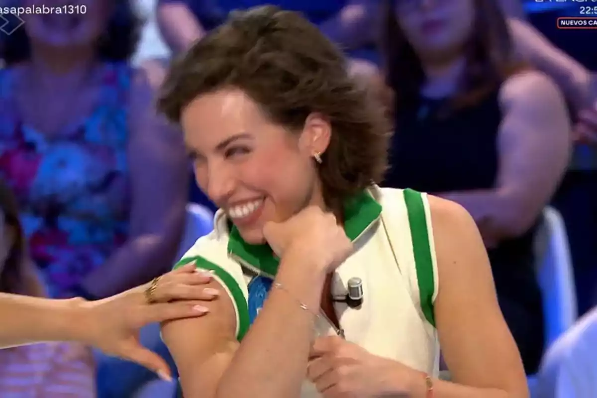 Rosa sonriendo y recibiendo una palmada en el brazo durante un programa de televisión con público al fondo Rosa sonriendo y recibiendo una palmada en el brazo durante un programa de televisión con público al fondo