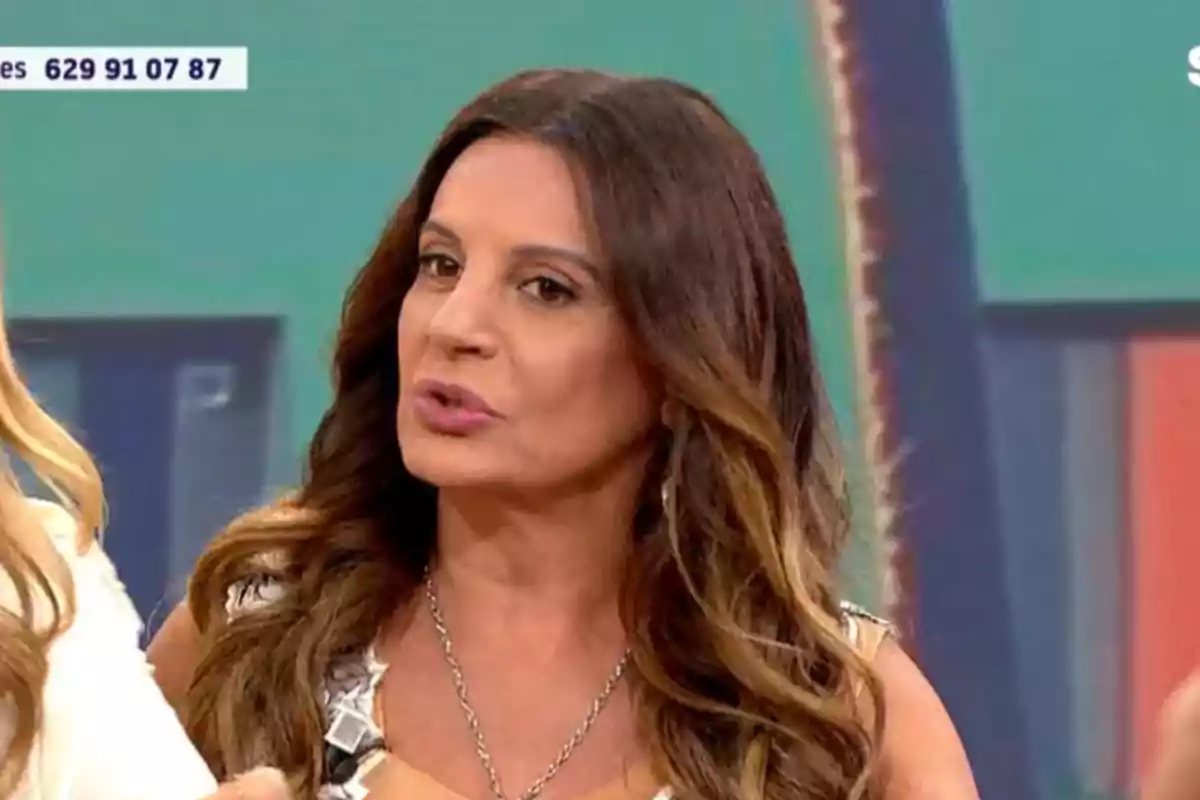Dona de cabell llarg i ondulat castany parlant en un programa de televisió amb un fons acolorit