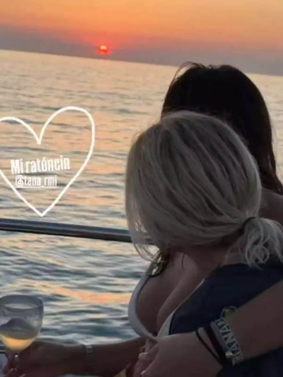 Tana Rivera y Eugenia Martínez de Irujo sentadas en un bote al atardecer mirando el mar, una de ellas sostiene una copa de vino y hay un corazón dibujado con la palabra Miratóncin Tana Rivera y Eugenia Martínez de Irujo sentadas en un bote al atardecer mirando el mar, una de ellas sostiene una copa de vino y hay un corazón dibujado con la palabra Miratóncin