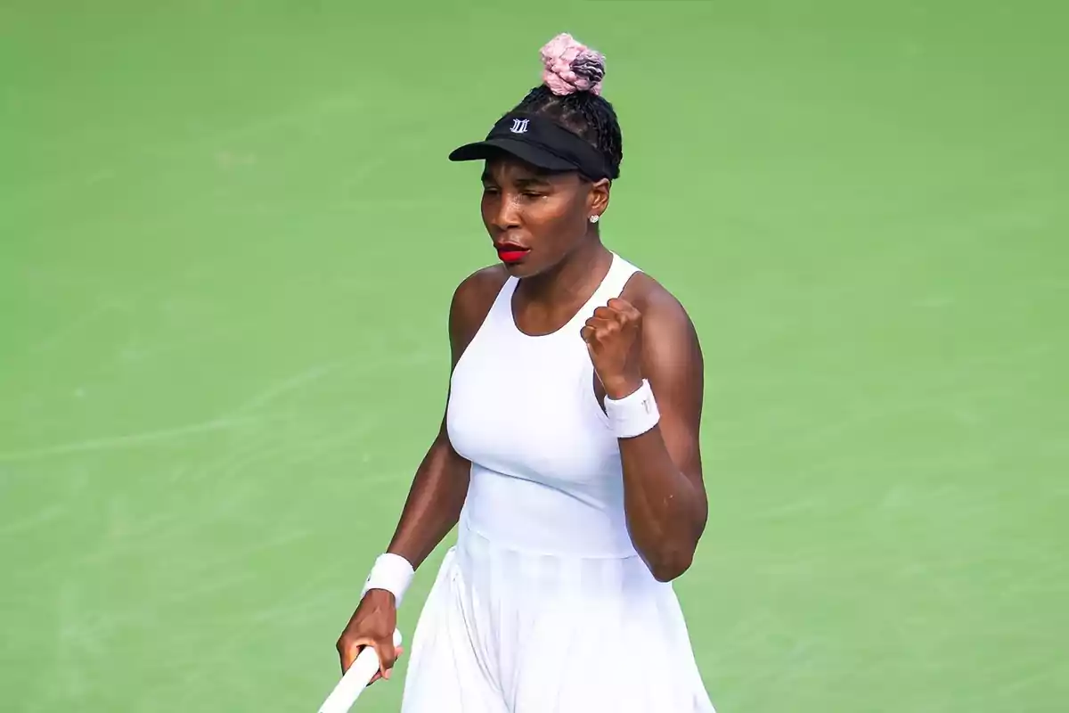 Venus Williams celebrando un punto en una cancha de tenis con vestimenta blanca y visera negra Venus Williams celebrando un punto en una cancha de tenis con vestimenta blanca y visera negra