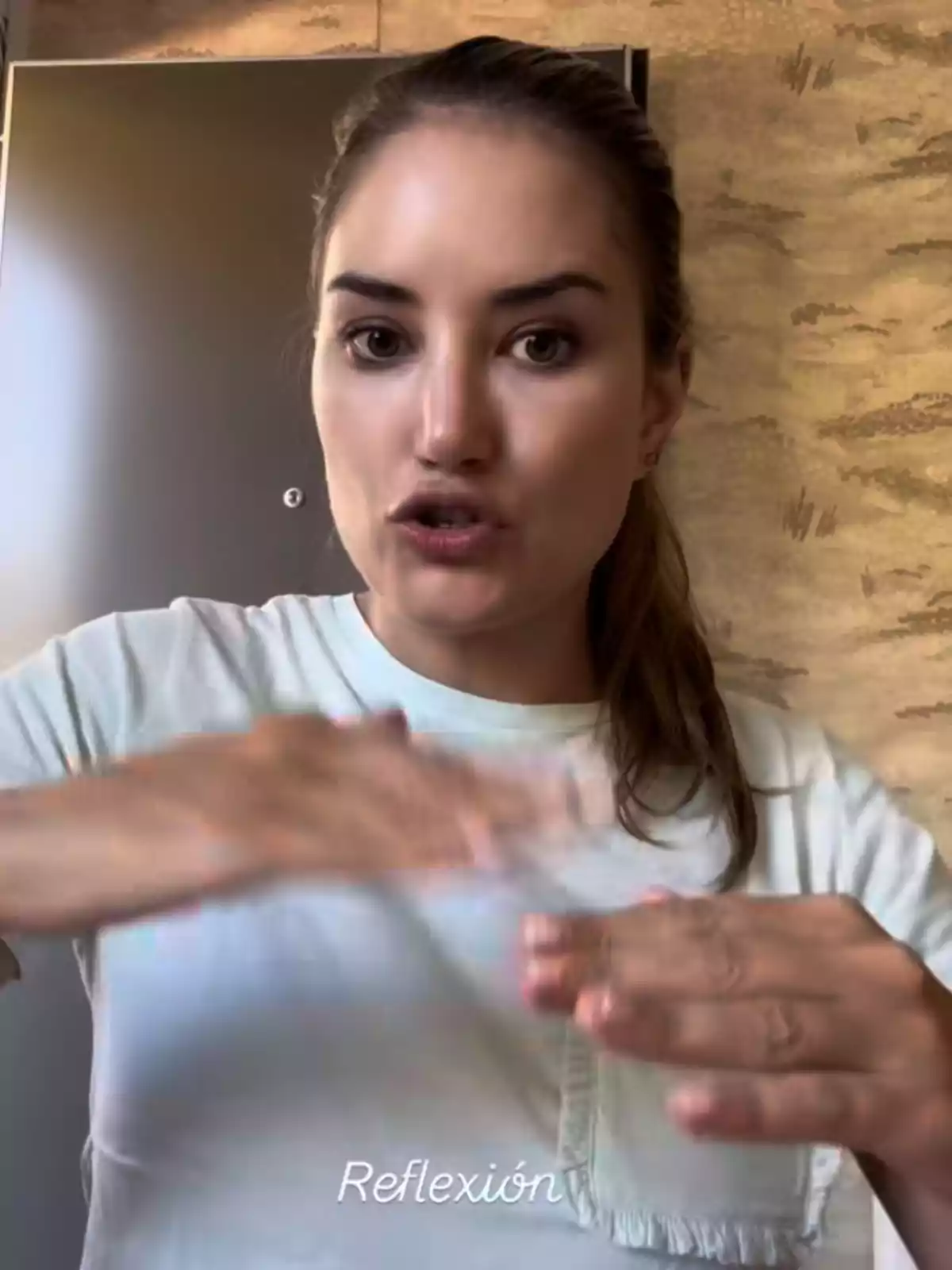 Alba Carrillo joven con camiseta blanca haciendo un gesto con las manos y la palabra Reflexión escrita en la parte inferior Alba Carrillo joven con camiseta blanca haciendo un gesto con las manos y la palabra Reflexión escrita en la parte inferior